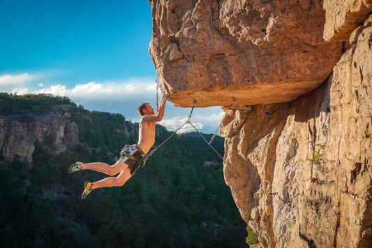 Man hanging from a cliff demonstrating grip strength and hand endurance
